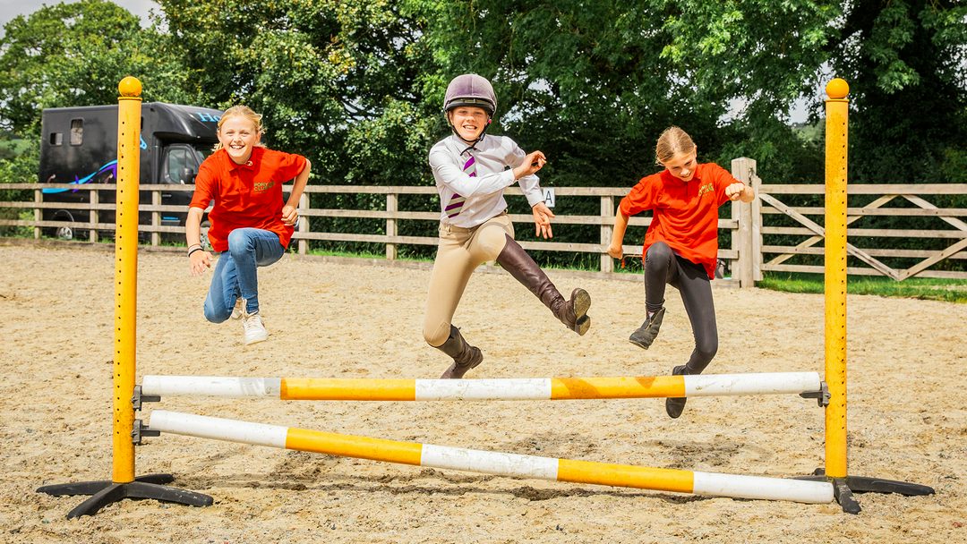 سه عضو Pony Club در اردوگاه Pony Club در حال پریدن از روی مانع نمایش پرشی به صورت پیاده
